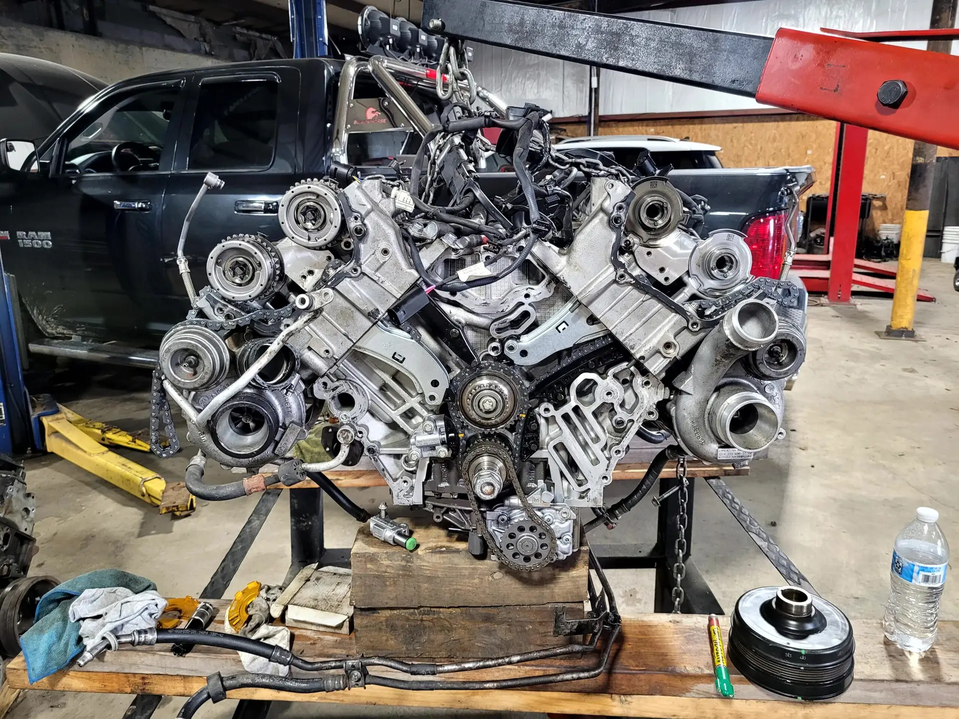 An automotive engine suspended on a hoist during a full engine replacement service.